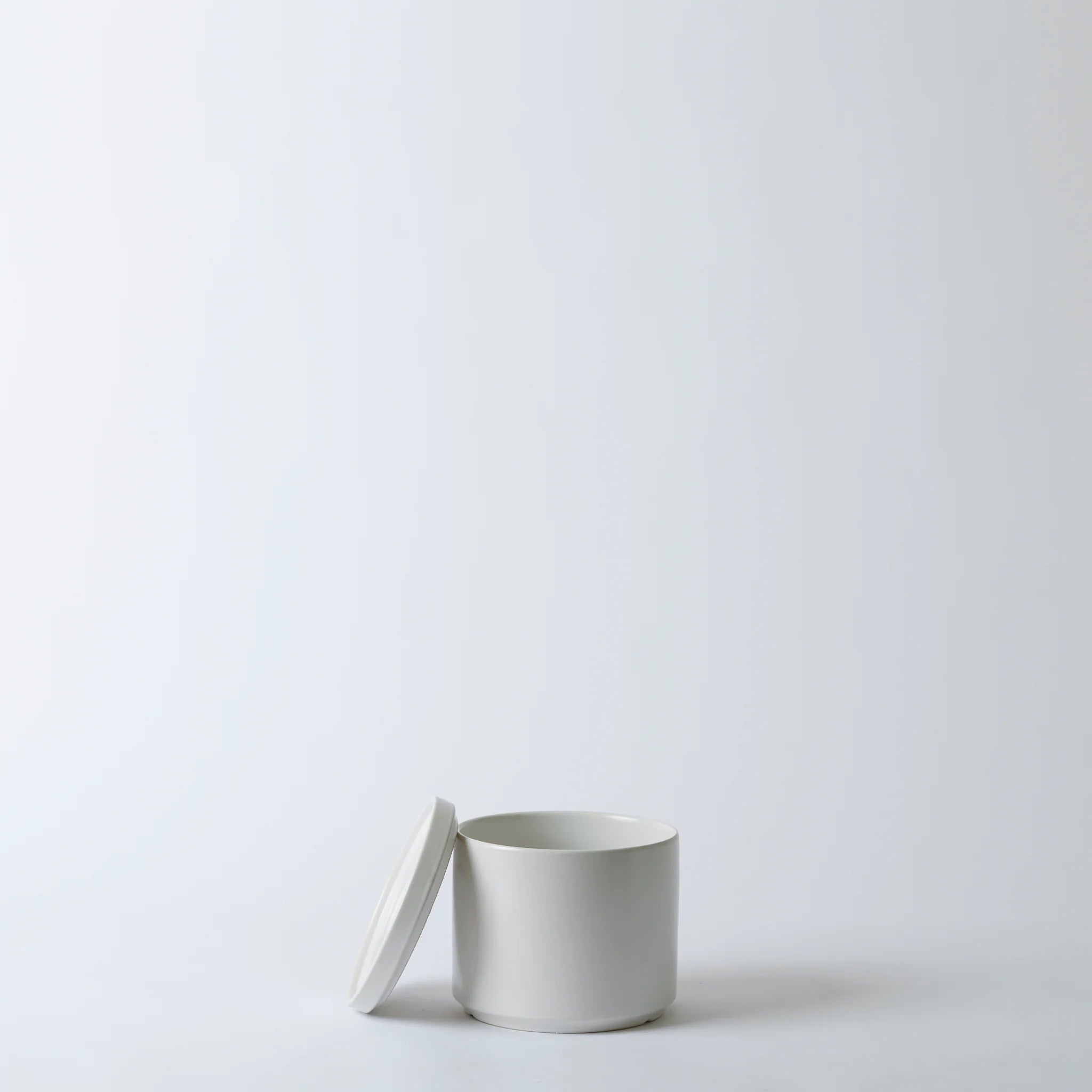 White ceramic container with lid on a light gray background