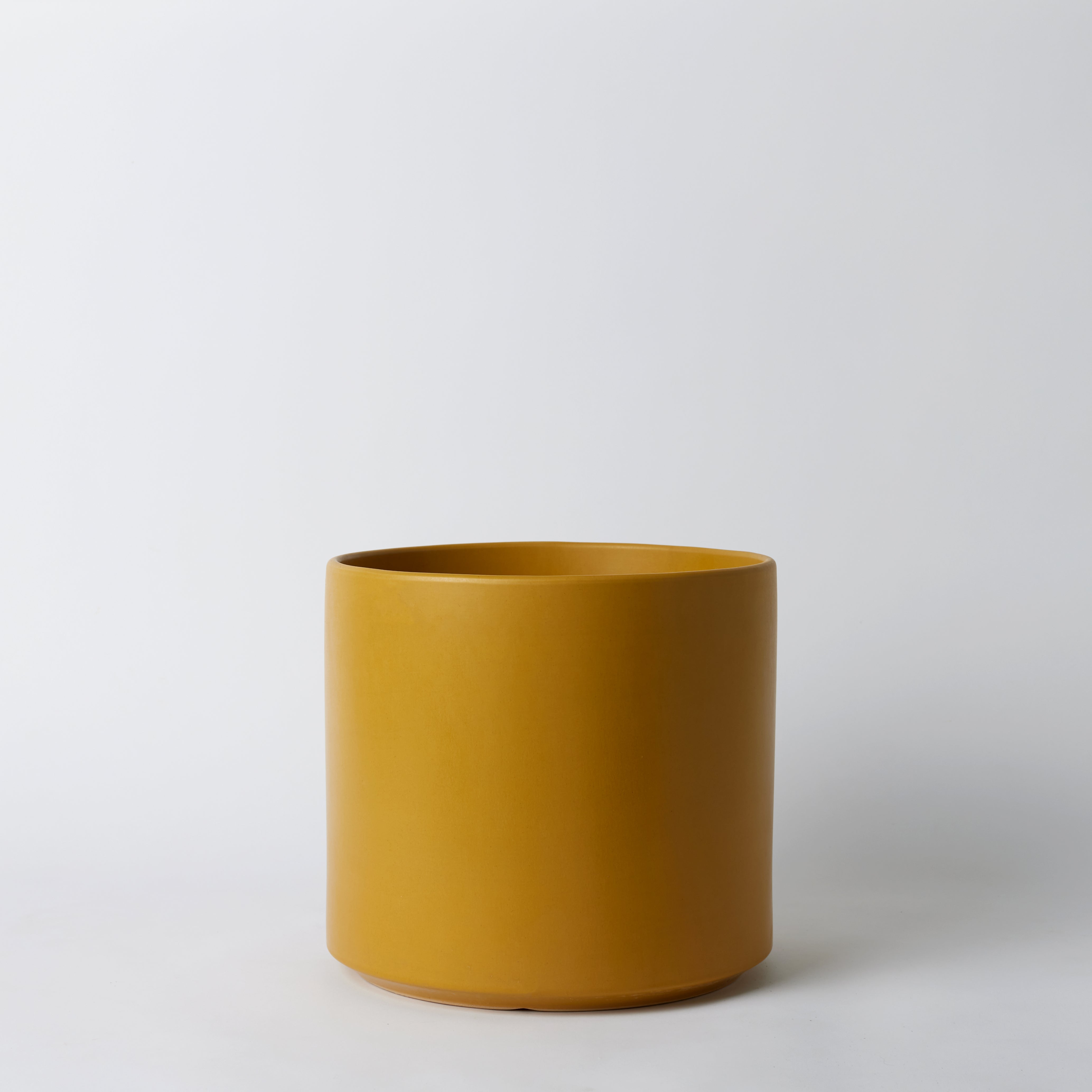 Mustard ceramic pot on a white background