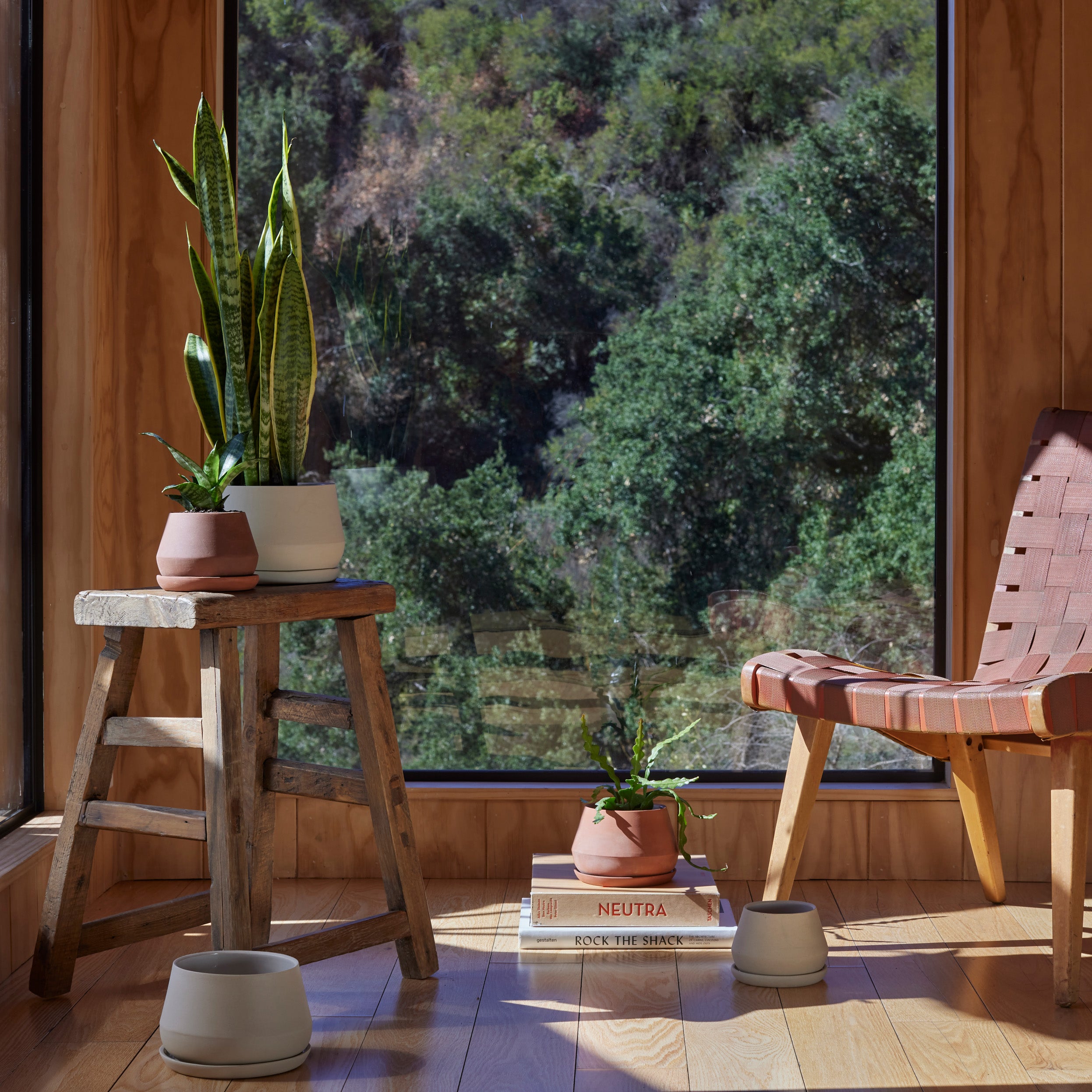 Lifestyle photo of sand and terra cotta colored Rancho Planters, staged in a corner of a cozy wooded home.
