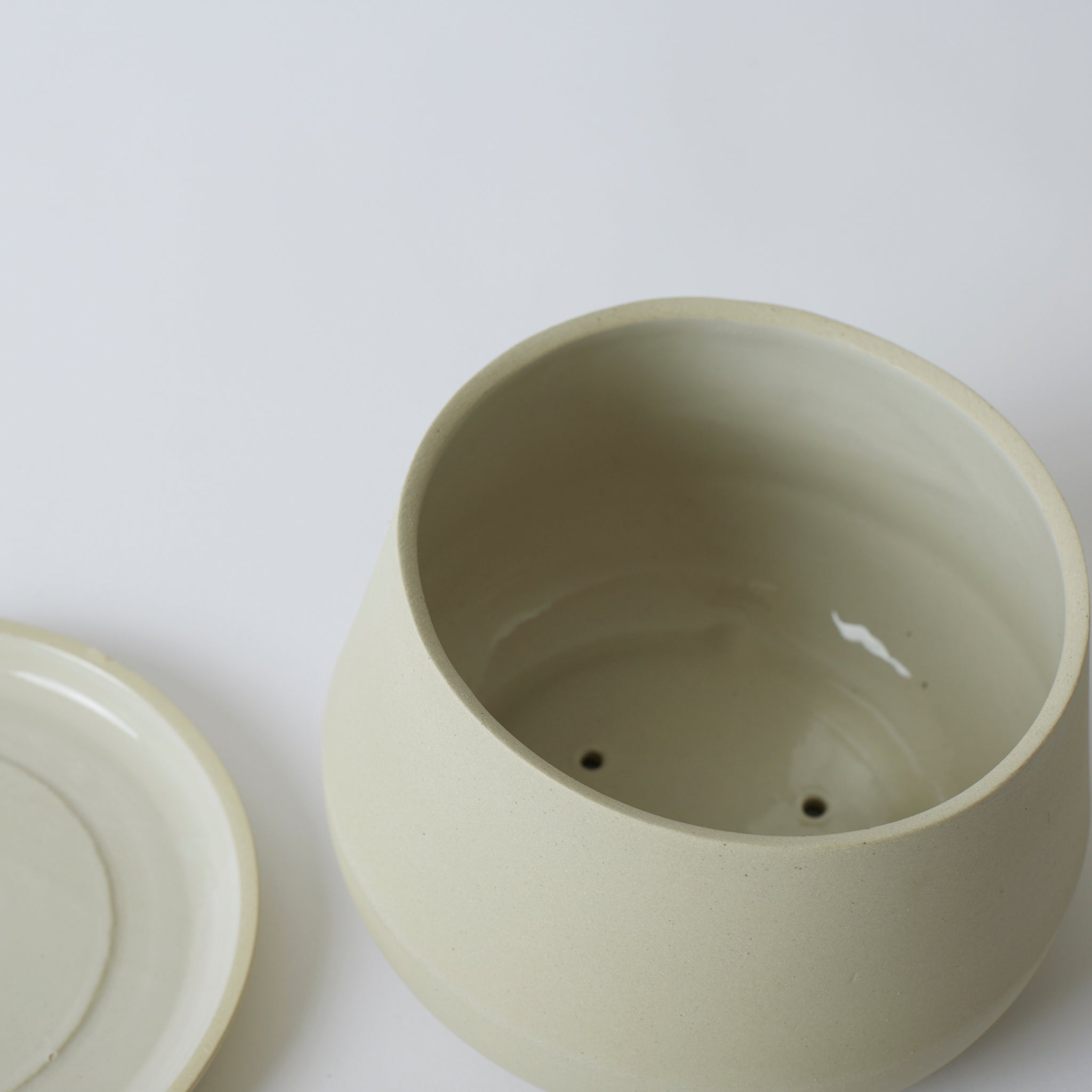 Silo photo of a sand colored Rancho Planter, showing the inside of the pot which has a shiny glazed inside and drainage holes.