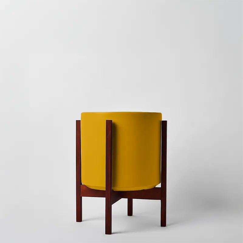 Mustard 12 Inch planter with dark square stand on a light gray background