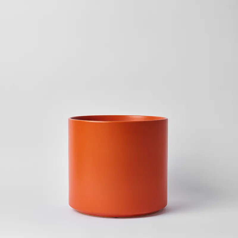 Rust cylindrical pot on a light gray background