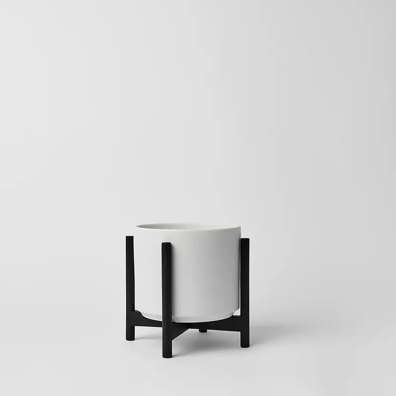 White 6 inch planter with black rounded stand on a light gray background
