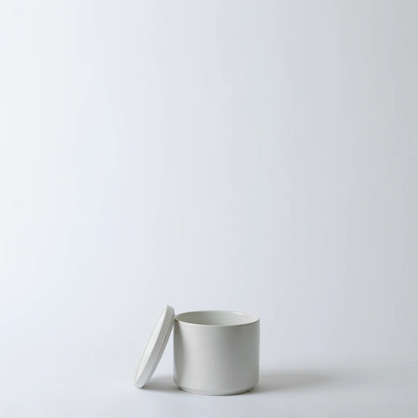 White ceramic container with lid on a light gray background