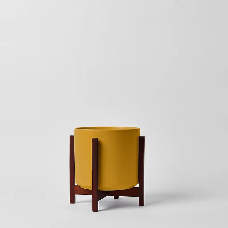 Mustard 8 Inch  planter with dark square stand on a light gray background