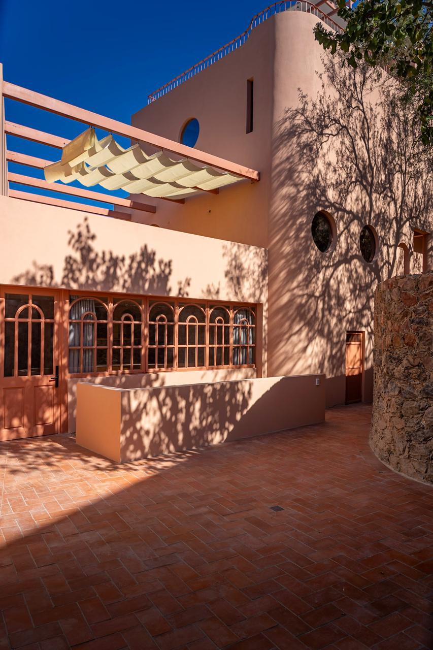 Exterior of the renovated Casa Slipper studio, pink stucco facade with arched windows